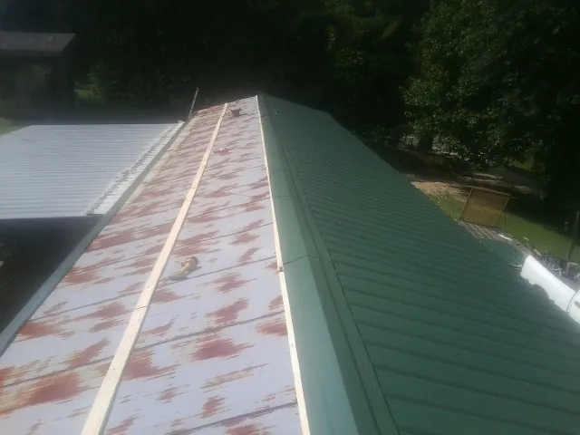 Old rusted panels beside newly installed green metal roofing — Wind Damage Roof Repair by Roofing Brothers in Apison