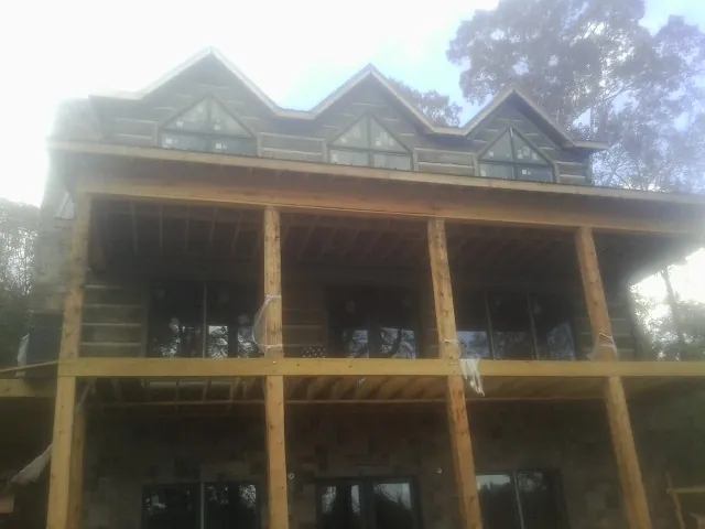 Dormers and porch framing on a large log home under construction — Roof Coating work by our crew in Apison