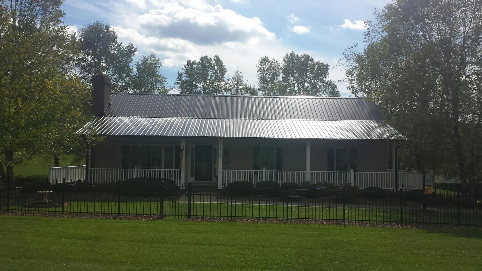 Gray metal roof on a brick ranch with a full width front porch — Gutter Guard Installation work by our crew in Apison